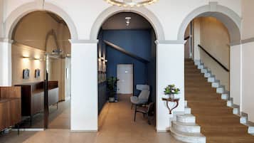 Un interior moderno con una escalera, arcos y una recepción con mostrador y asientos.
