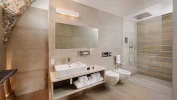 A modern bathroom with a stone arch, a large mirror, a sink, a toilet, and a shower.