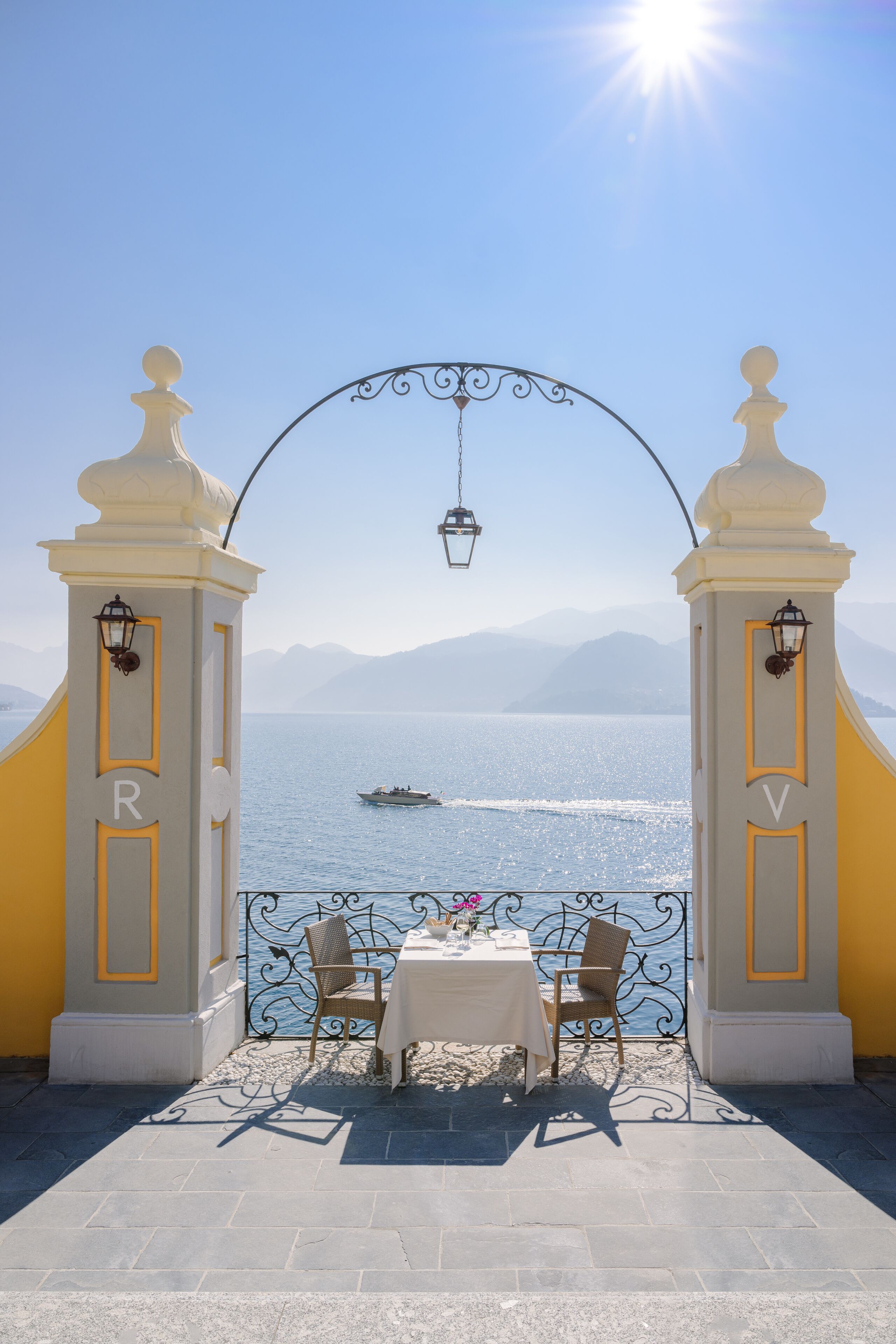 A dining area with a table and chairs, a view of the sea, and a clear sky.