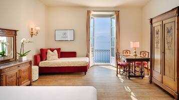 A room with a red sofa, a wooden cabinet, a dining table with chairs, and a view of the outdoors.