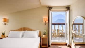 Ein Hotelzimmer mit einem großen Bett, einem Nachttisch mit Lampe, einem kleinen Tisch mit Pflanze und einem Balkon mit Stuhl und Tisch.