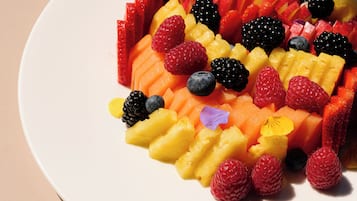 Un piatto bianco con una varietà di frutta tagliata, tra cui fragole, mirtilli, lamponi e ananas.