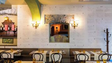 A restaurant interior with tables set for dining, wall-mounted menu boards, and wall-mounted lighting fixtures.
