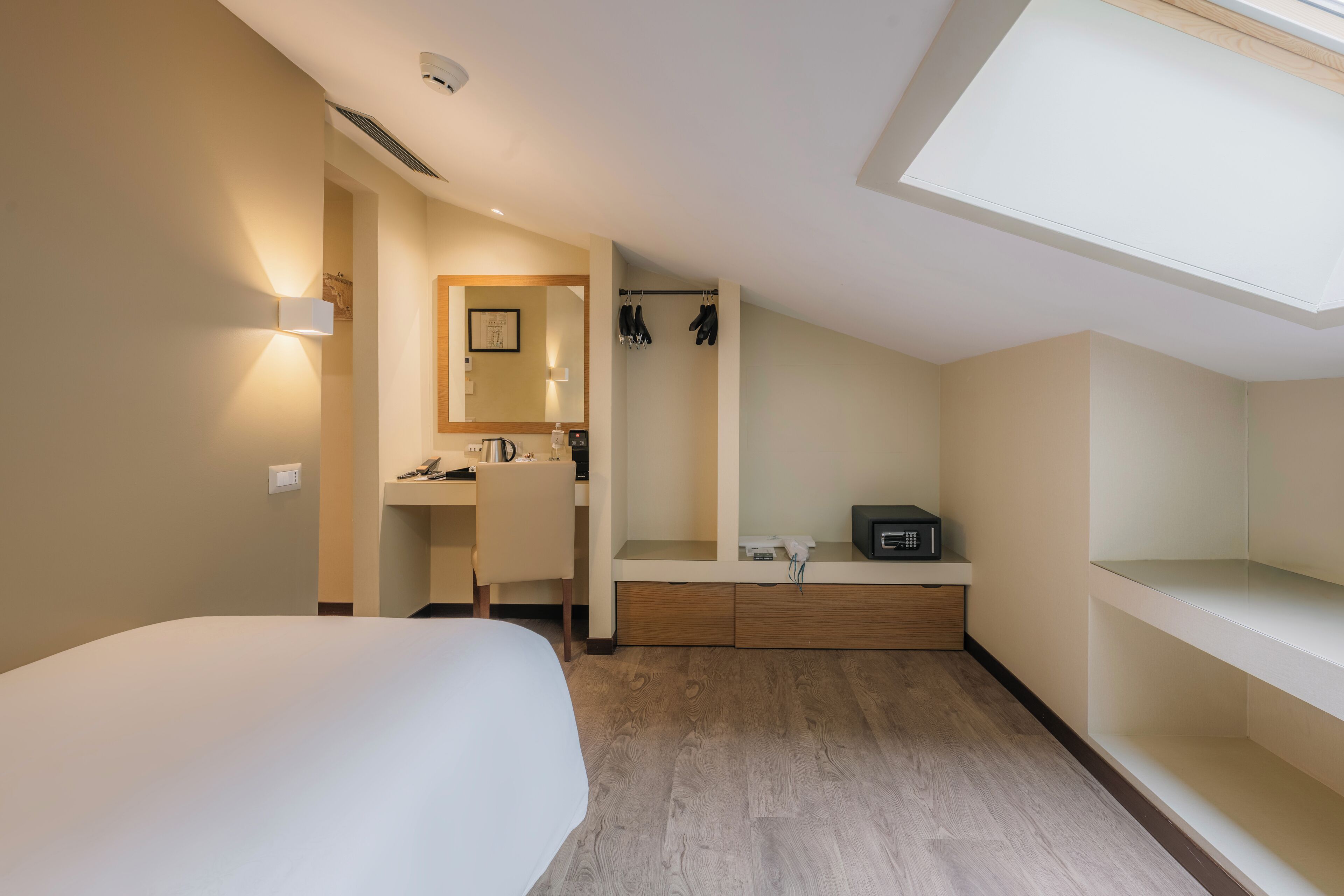 A bedroom with a bed, a desk, a mirror, a sink, and a shower.