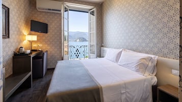 Una habitación de hotel con cama, mesita de noche, lámpara y televisor.