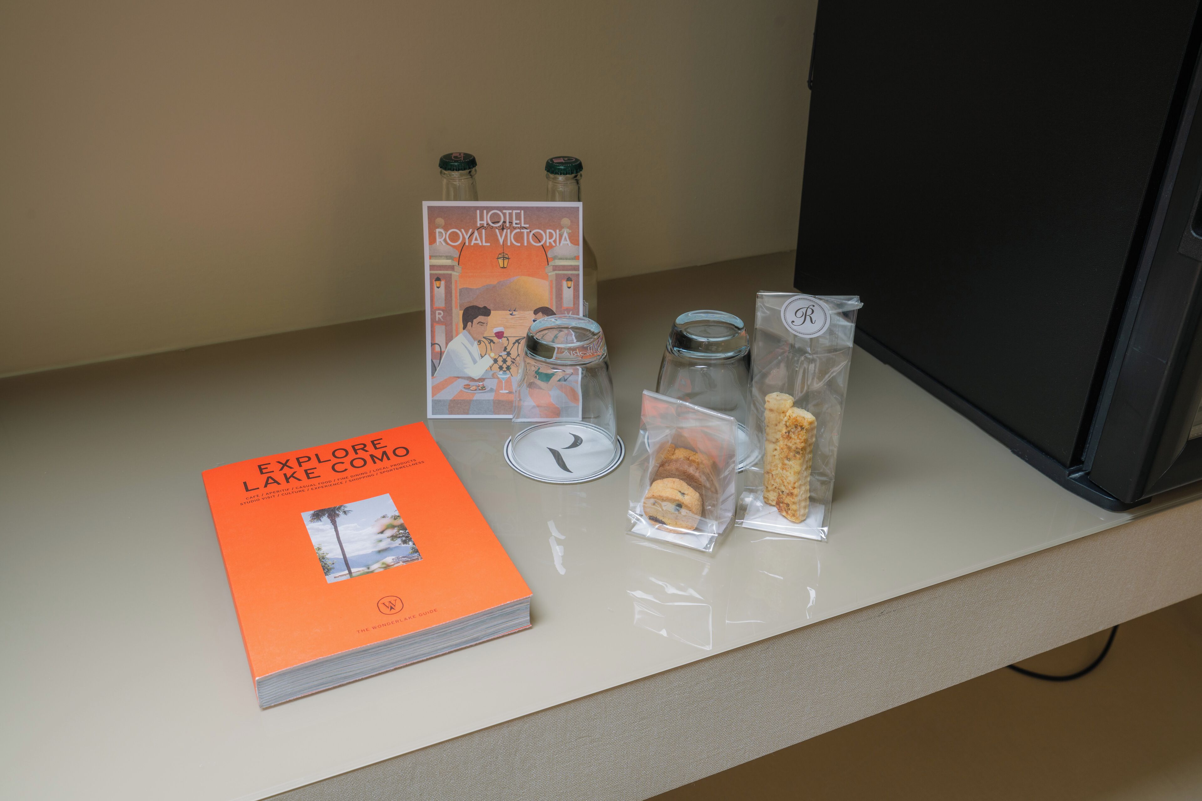 A hotel brochure, a book, and some packaged snacks on a counter.