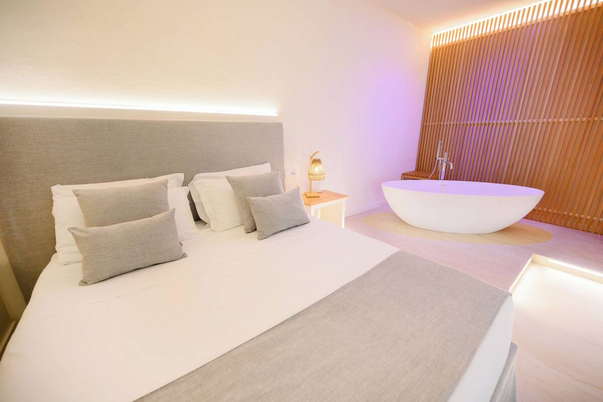 Un dormitorio moderno con una cama grande, mesitas de noche y una bañera integrada.