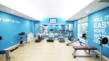 A gym with blue walls, various exercise equipment, and motivational quotes.