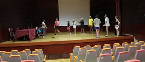 A stage with people standing and sitting in an auditorium with rows of chairs.