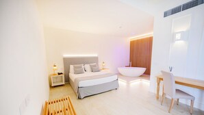 A modern bedroom with a bed, bedside tables, a desk, and a large bathtub.