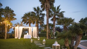 An outdoor wedding setup with a canopy, white tablecloth, and lanterns.