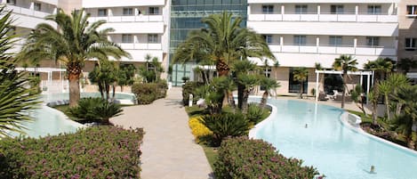 Un hotel con piscina, palmeras y cielo despejado.