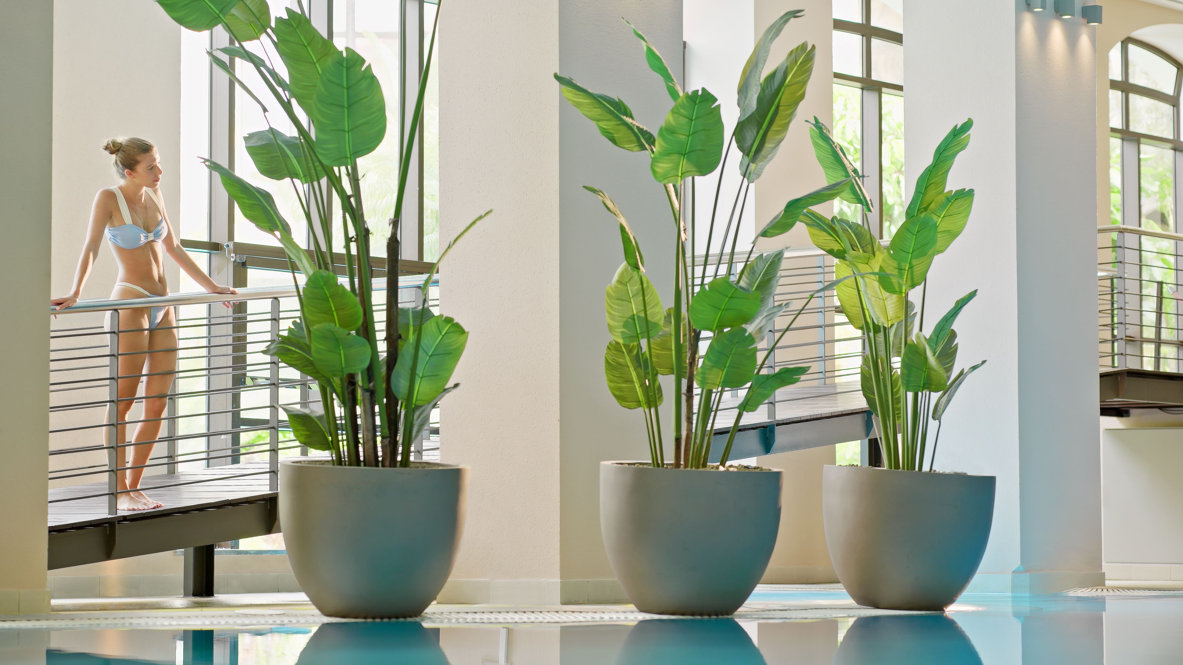 A pool area with potted plants and a person in swimwear.
