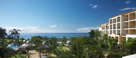 A resort with a pool, palm trees, and a view of the ocean.