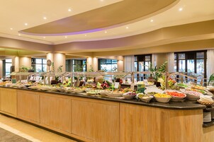 Un buffet proposant une grande variété de plats, notamment des salades, des fruits et d’autres mets, disposés sur un long comptoir au revêtement en bois.
