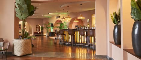A modern bar area with wooden flooring, bar stools, and ambient lighting.