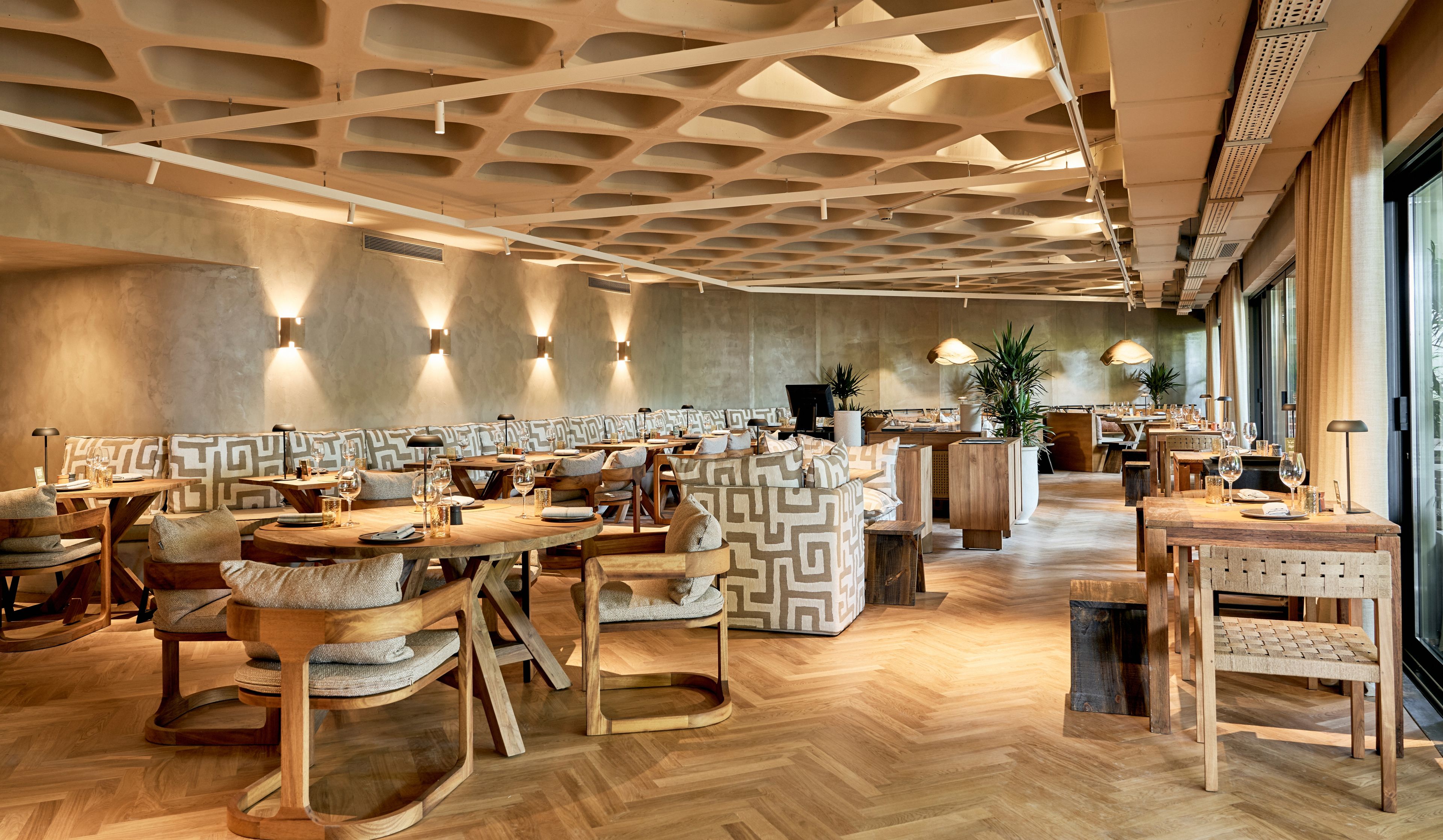 En restaurang med trämöbler, mönstrade kuddar och en unik takdesign.