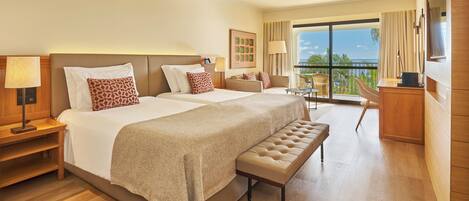 A hotel room with a large bed, a bench, a desk, and a balcony with a view.