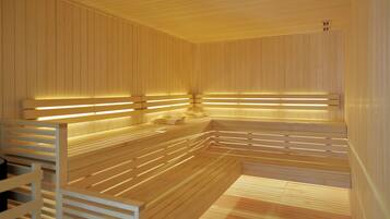 Een sauna met houten banken en lambrisering, verlicht met inbouwverlichting.