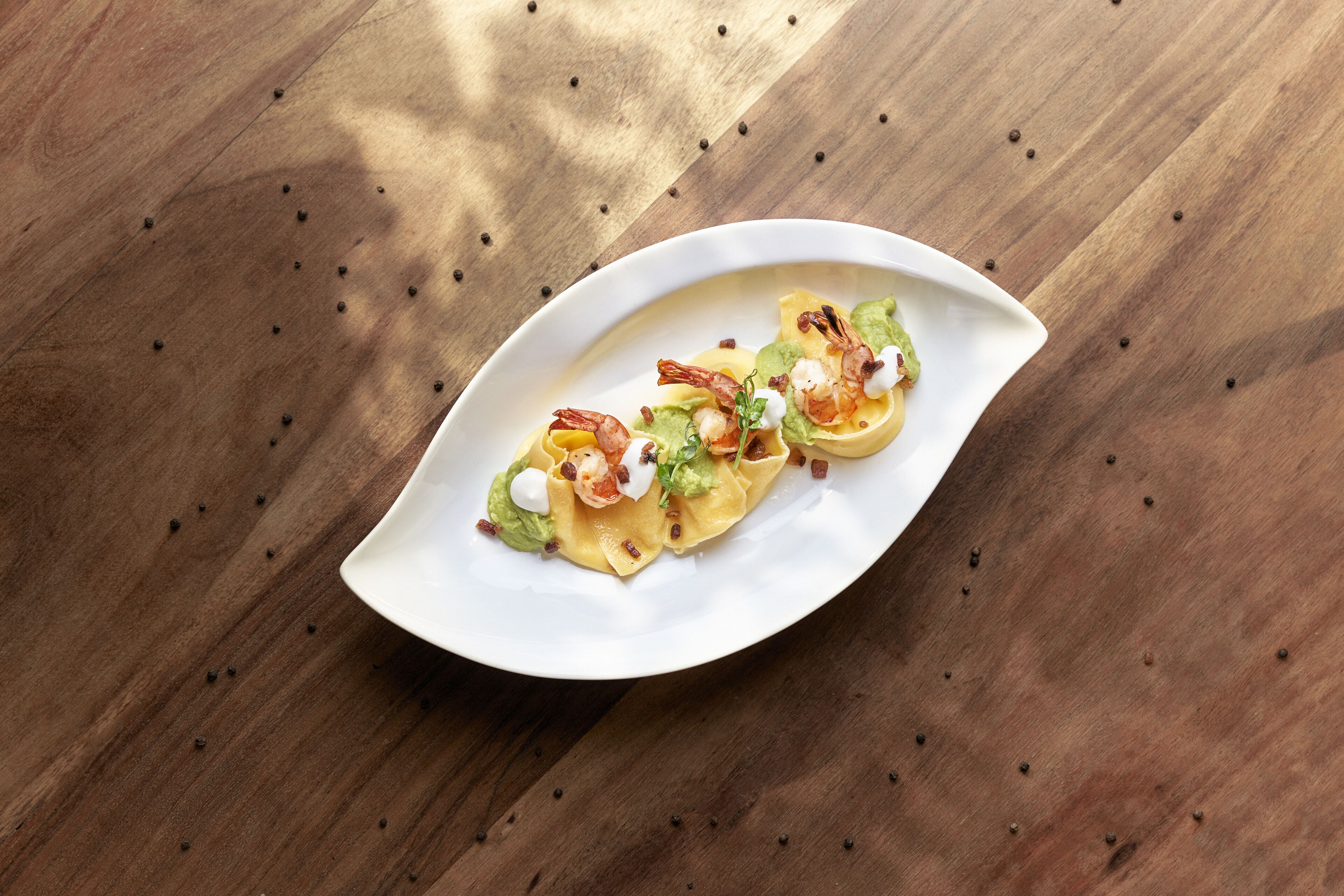 A white plate with a dish on a wooden table.