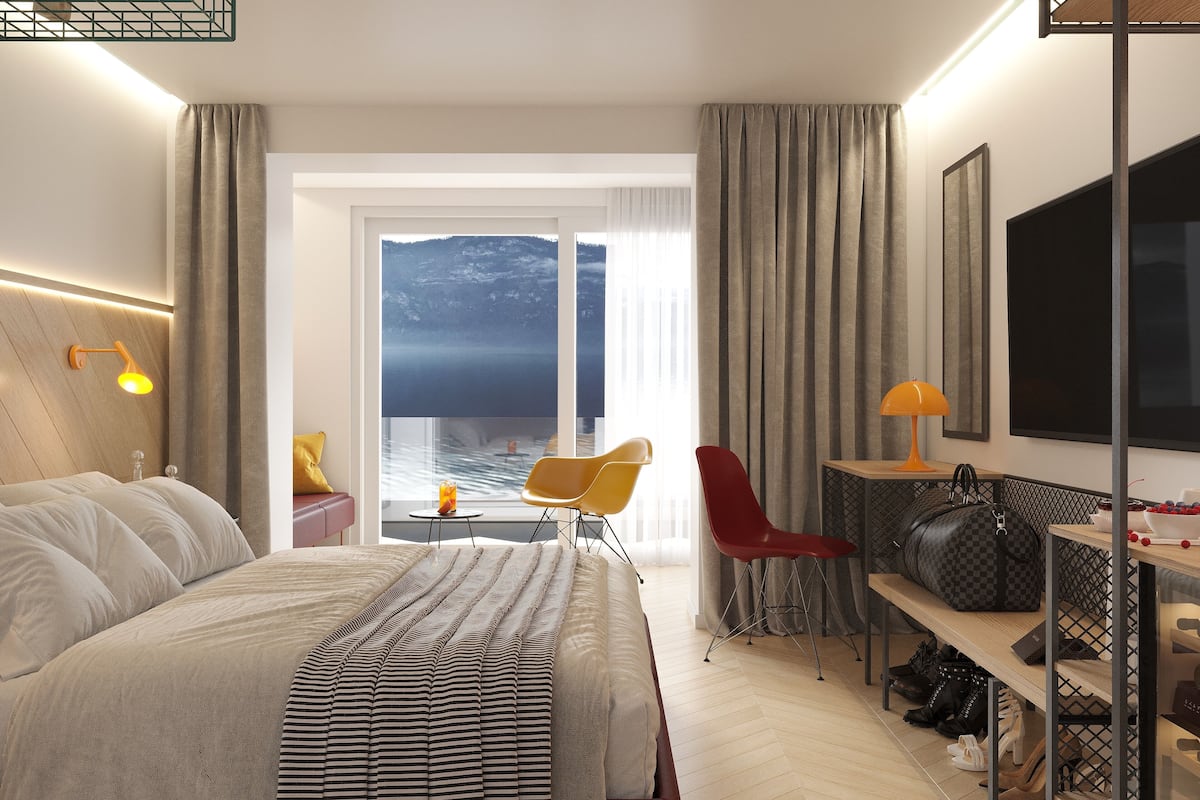 Quarto de hotel com uma cama, uma escrivaninha, uma cadeira, uma televisão e vista para a água.