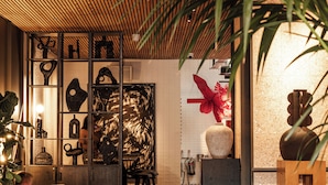 A modern interior with a wooden ceiling, a seating area with a laptop user, and various decorative items. - One Hundred Shoreditch (London)