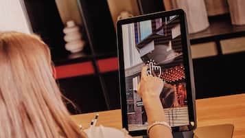 Eine Person benutzt ein Tablet mit Tastatur, ein Zahlungsterminal und ein Smartphone auf einem Holztisch.