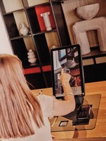 Eine Person benutzt ein Tablet mit Tastatur, ein Zahlungsterminal und ein Smartphone auf einem Holztisch.