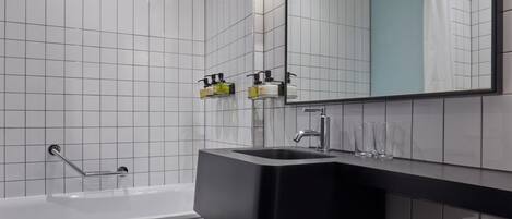 Une salle de bain moderne avec un lavabo noir, des carreaux blancs, une douche en verre et un miroir au-dessus du lavabo.