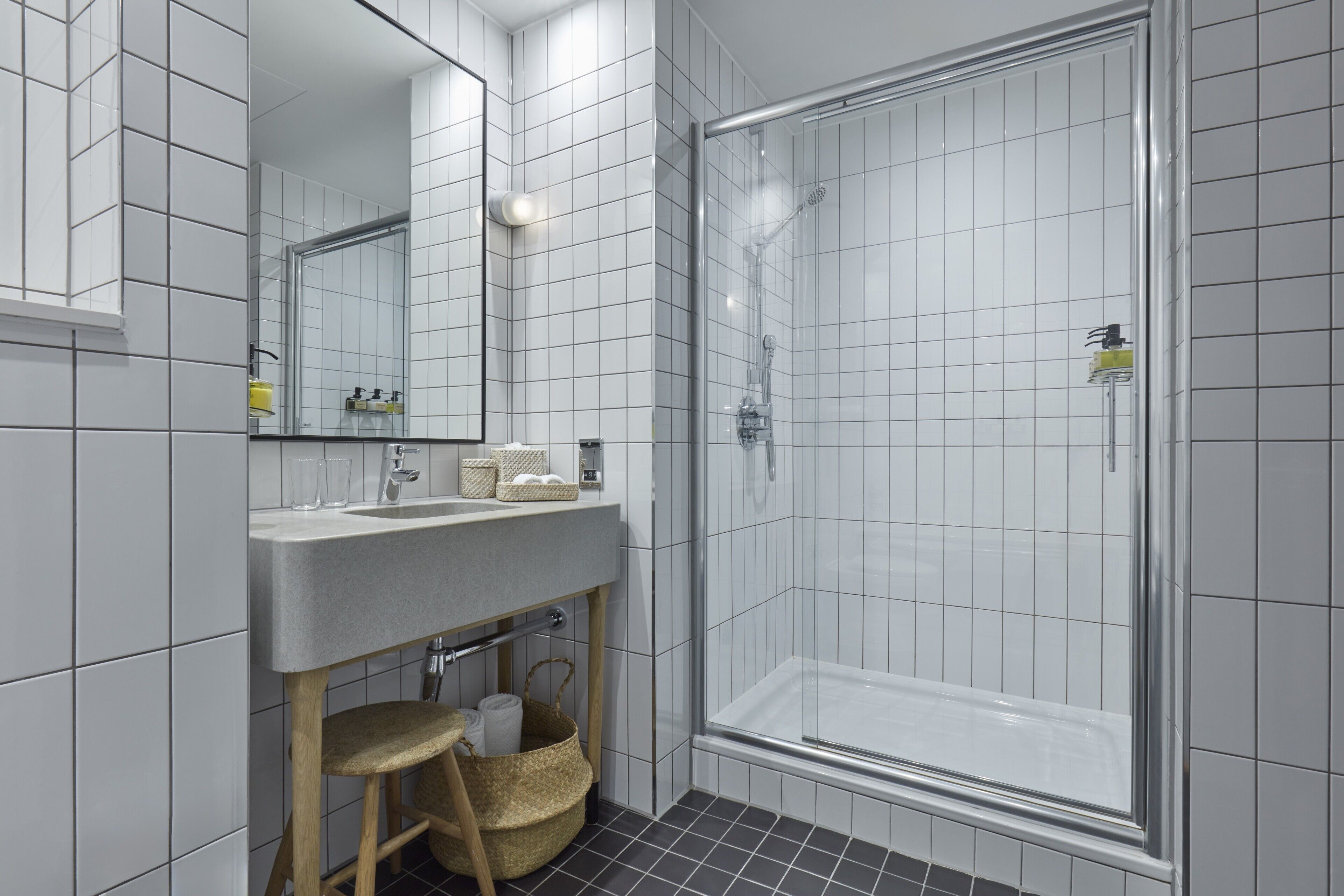 A modern bathroom with a large mirror, a sink, and a glass-enclosed shower.