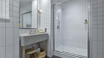 A modern bathroom with a large mirror, a sink, and a glass-enclosed shower.