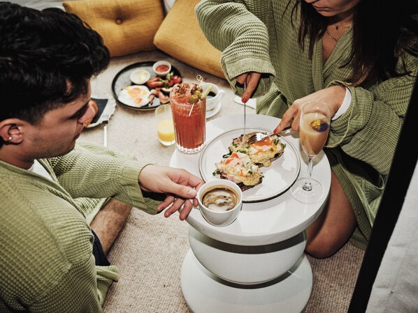 A dining table with a plate of food, a glass of drink, and a cup of coffee.