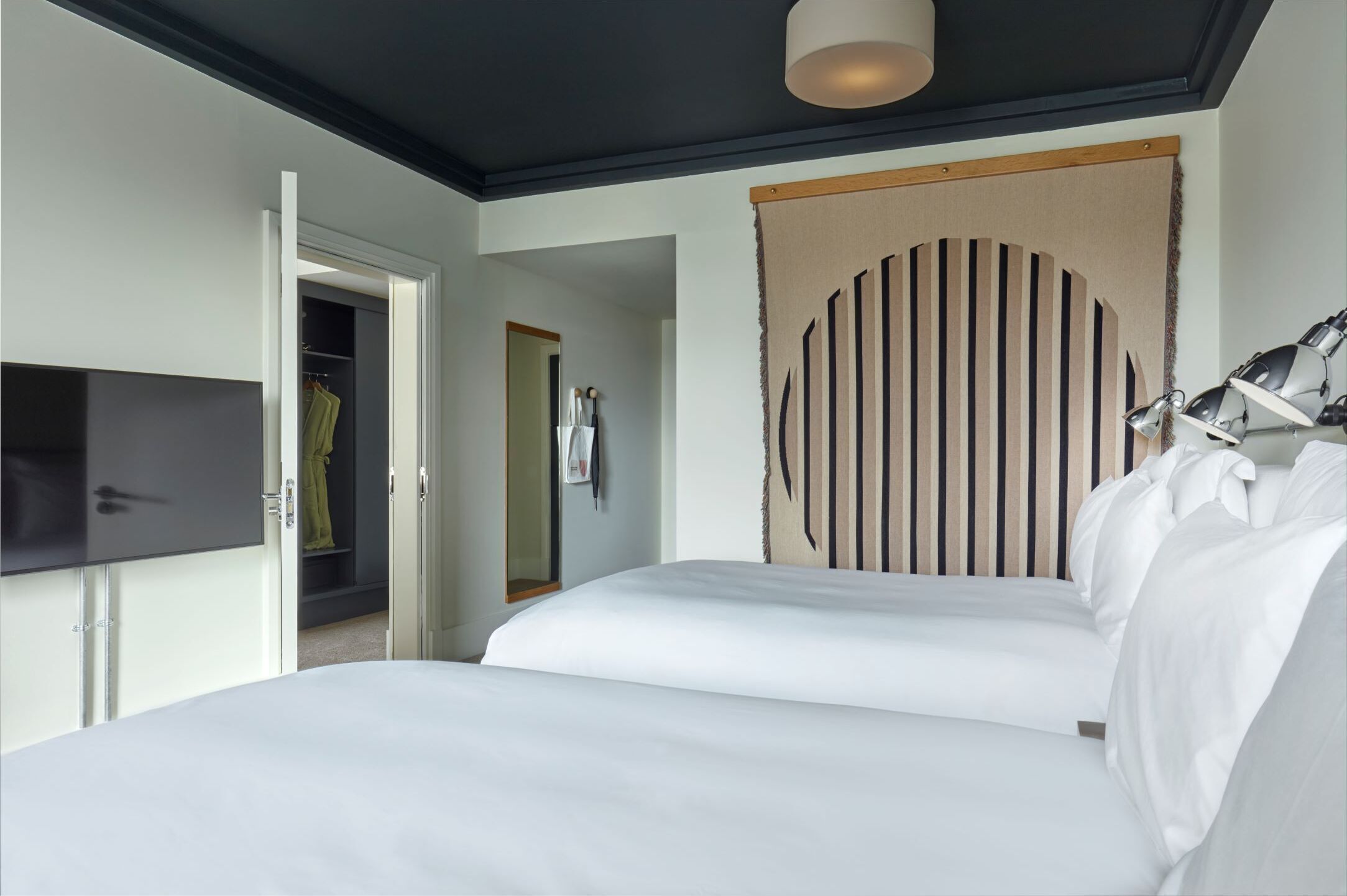 A hotel room with a bed, a TV, a wardrobe, and a unique wall decoration.