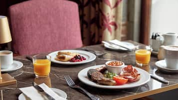 Una mesa de desayuno con platos de comida, un vaso de jugo de naranja y una taza de café.