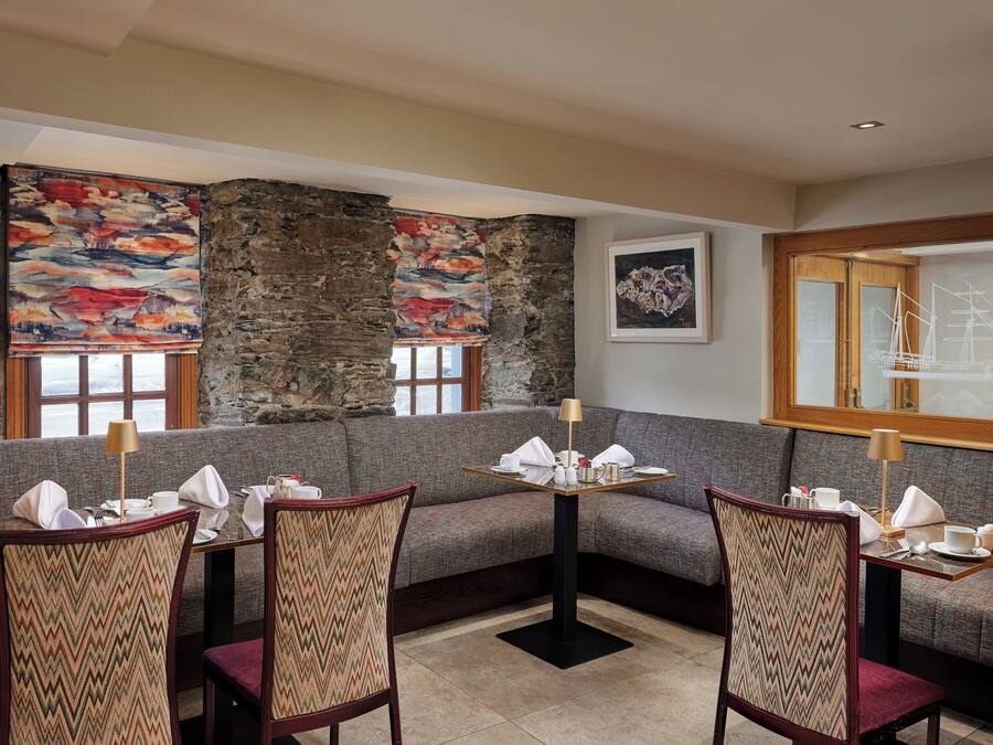 A dining area with a stone wall, a sofa, and a table set for two.