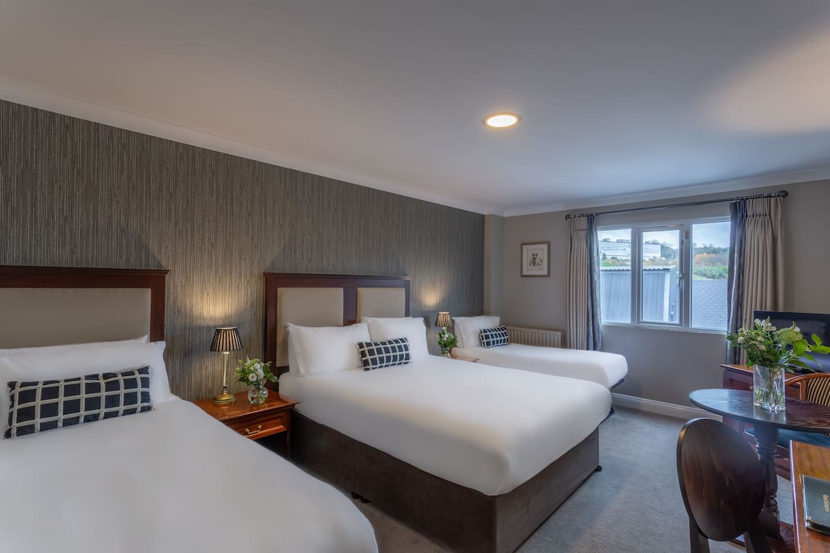 A hotel room with two beds, a desk, and a window with curtains.