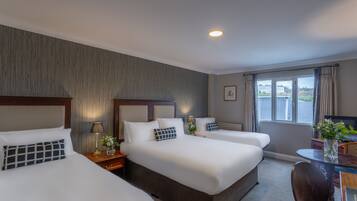 A hotel room with two beds, a desk, and a window with curtains.