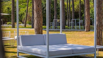 A white outdoor seating area with a metal frame, surrounded by trees.