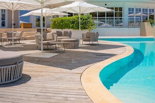 Un espace aménagé au bord de la piscine, avec des chaises longues, des parasols et une terrasse en bois.
