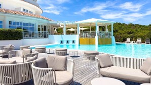 Un espace piscine avec des chaises longues et un coin salon abrité.