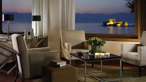 Una habitación de hotel moderna con vista a un castillo junto al agua al anochecer.