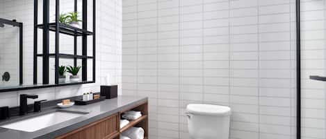Un baño moderno con tocador de madera, un espejo grande y un inodoro.