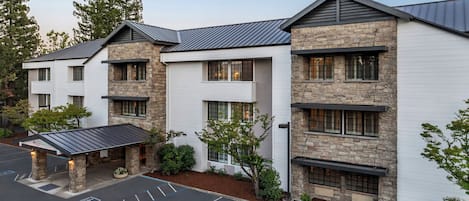 A multi-story hotel with a stone facade, multiple windows, and a parking lot.