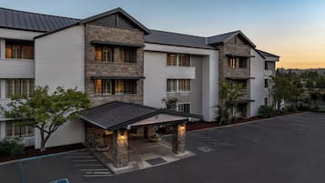 A multi-story building with a stone facade, a covered entrance, and a parking lot.