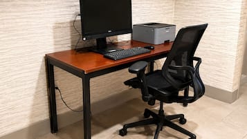 A wooden desk with a computer, keyboard, and printer.