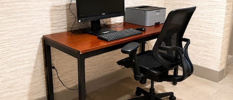 Un escritorio de madera con una computadora, teclado e impresora.