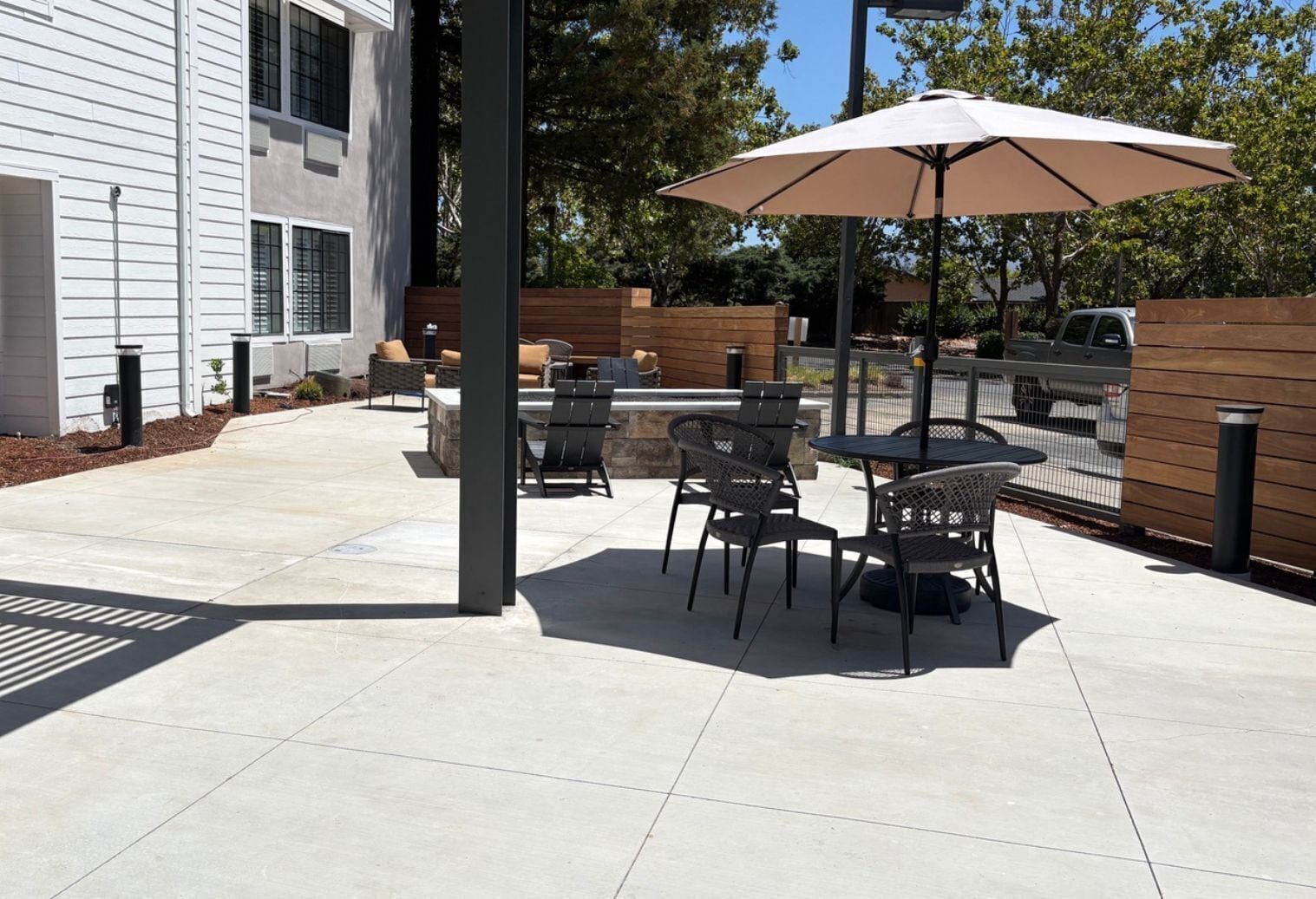 An outdoor patio with a table and chairs, a large umbrella, and a stone fireplace.