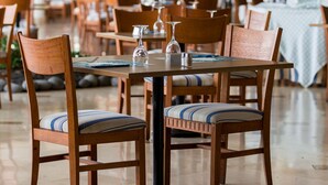 A spacious restaurant with wooden tables and chairs, a tiled floor, and a view of the outdoors. - Vitalclass Lanzarote Resort (Teguise)