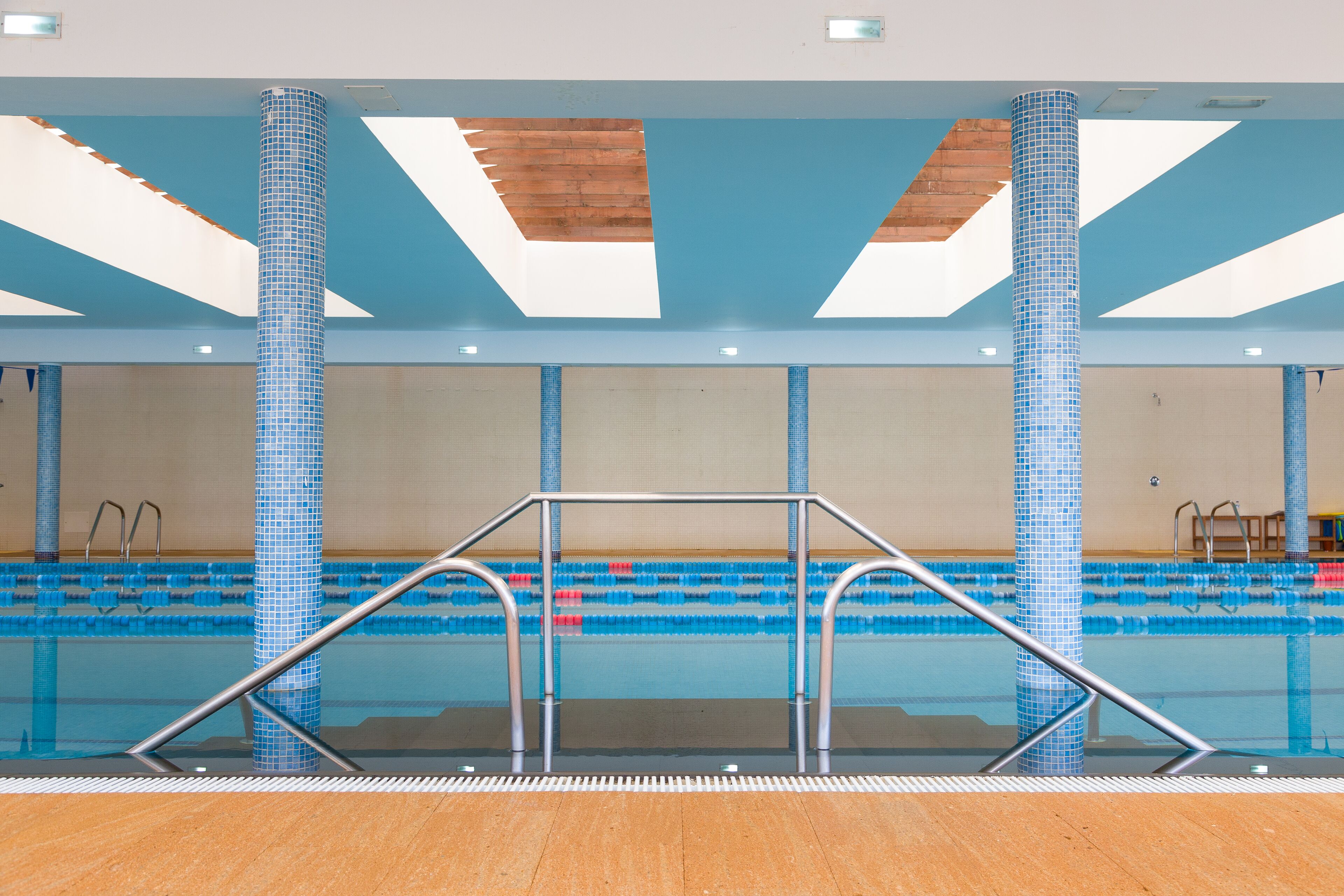Une piscine intérieure avec des couloirs bien délimités, un plongeoir et un sol en bois.