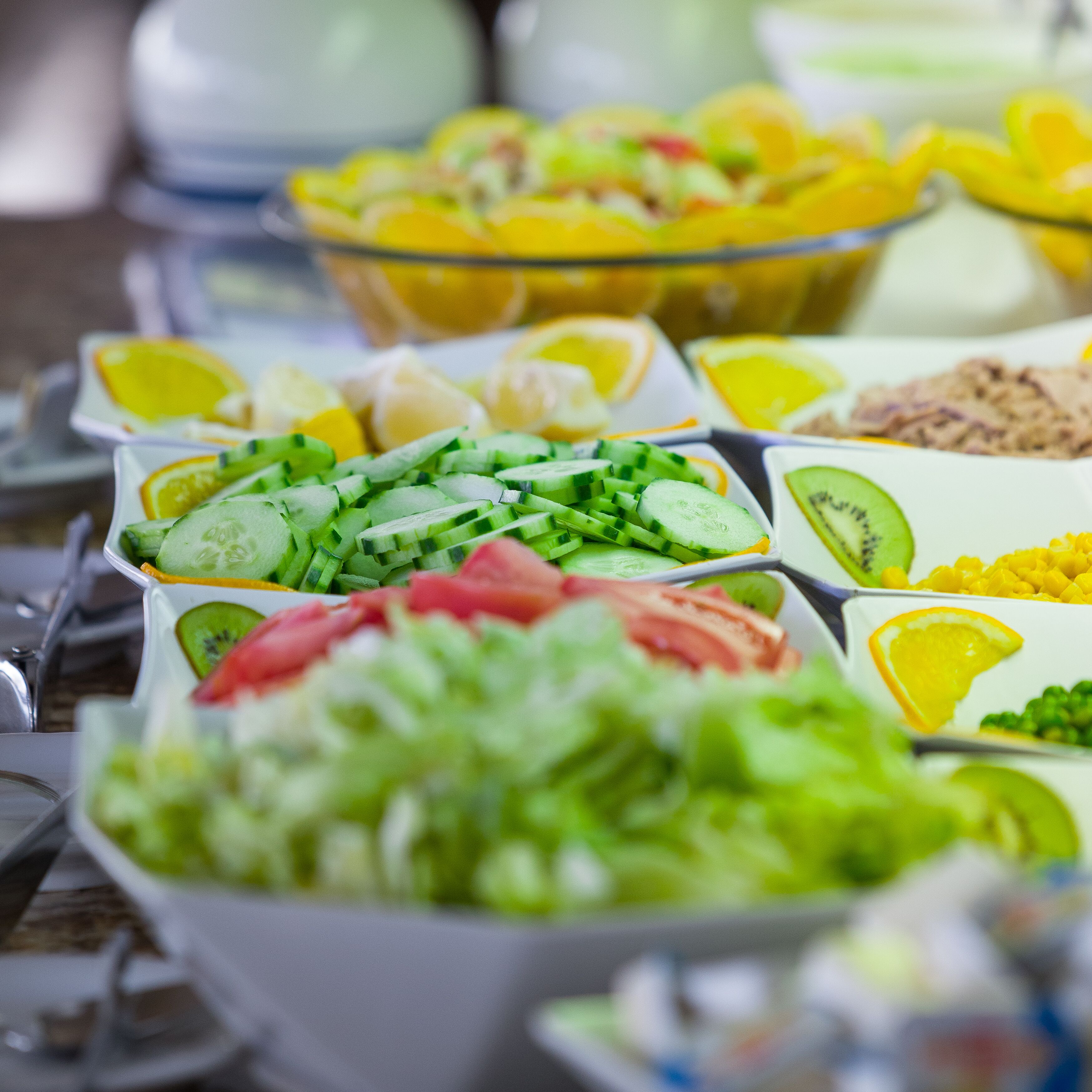 Een buffet met diverse gerechten, waaronder salades, fruit en groenten.